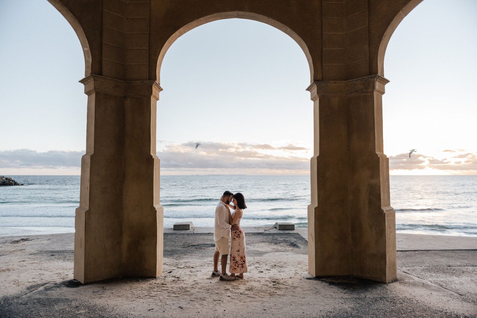 A couple poses for a photo at sunset at Cottesloe beach in Perth, Western Australia