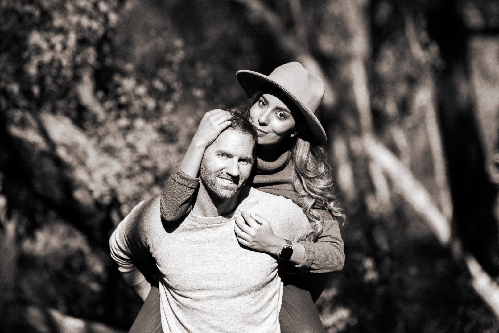 A man holds his partner on his back while she looks at the camera