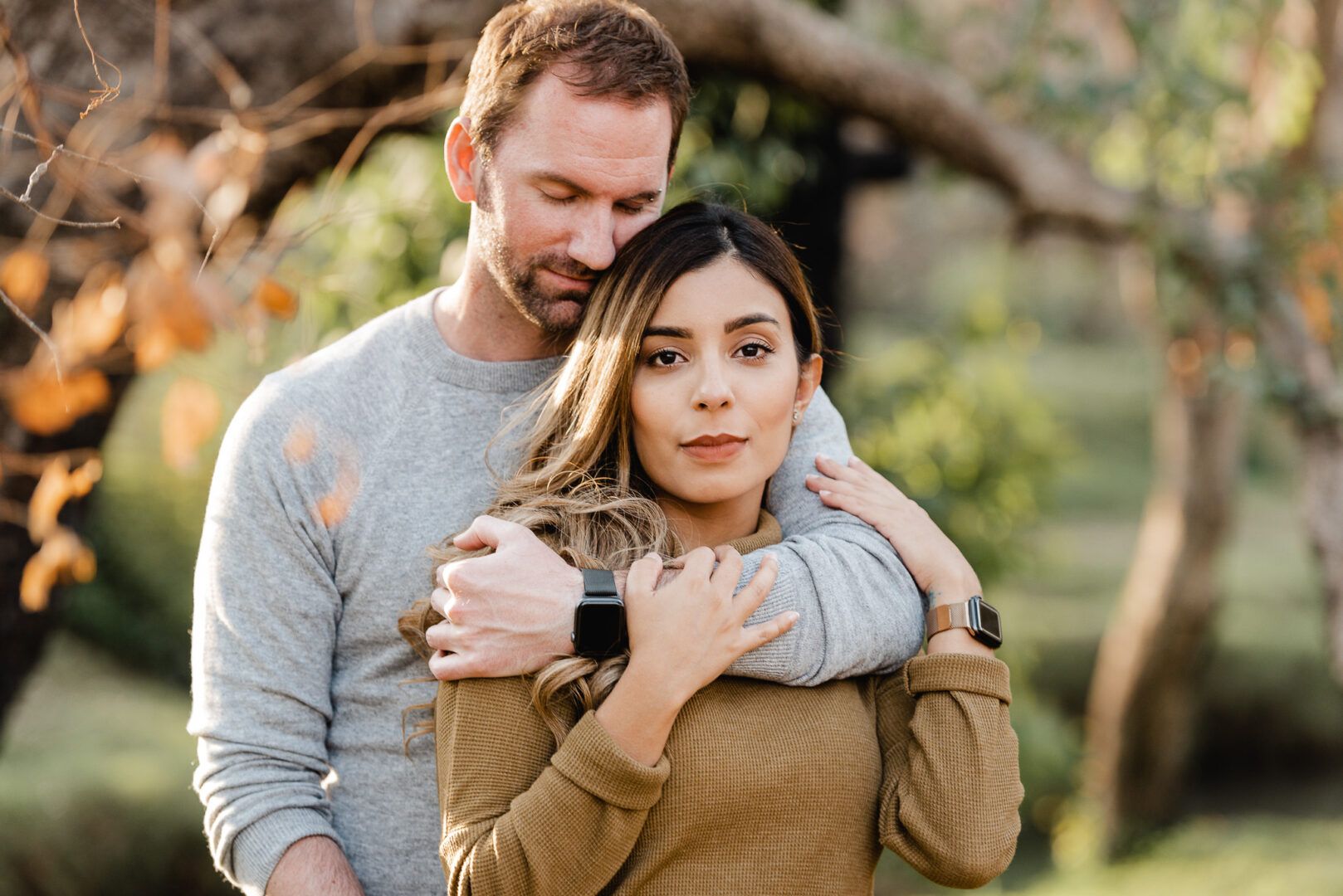 A girl loooks at the camera while her boyfriend hugs her from behind 