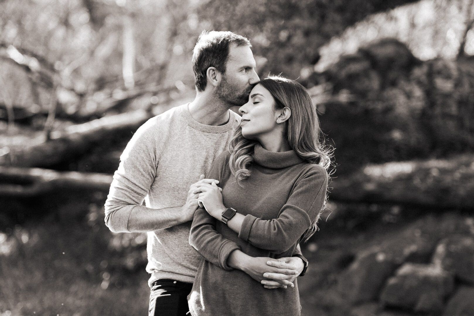 A man kisses his partner on the forehead while hugging her 