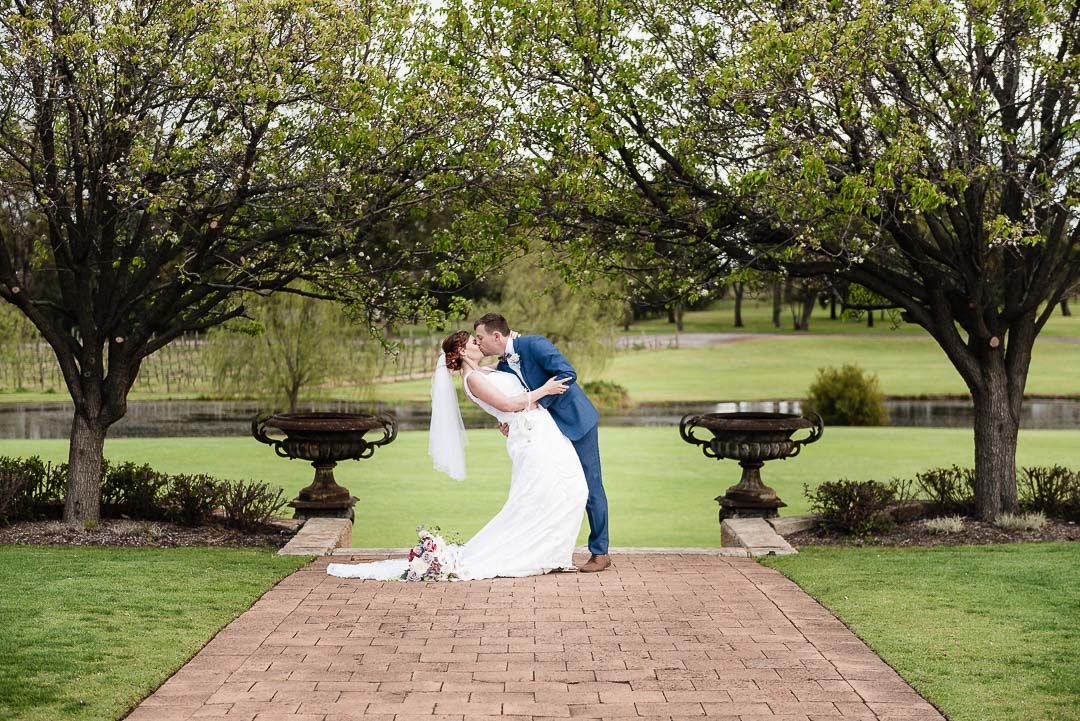 Bride and groom kiss in front of a grass field at Sandalford Wines