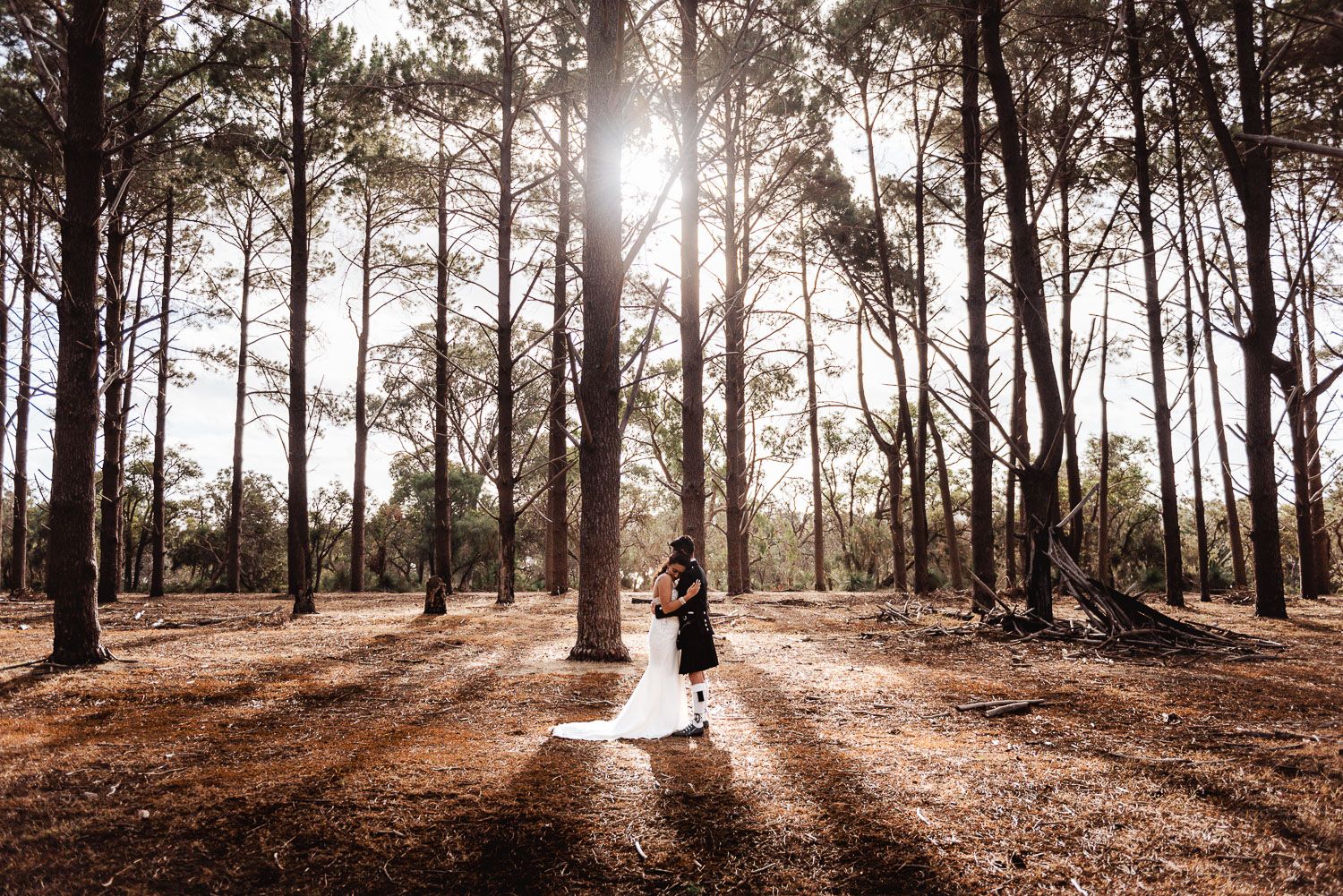 Bride and groom hugh while standing in a forest in Wanneroo Pines